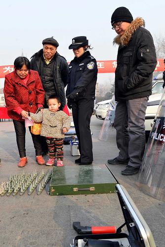 1月10日,济南市公安局历城区分局民警在向市民介绍“110”警用装备。新华社记者 朱峥 摄
