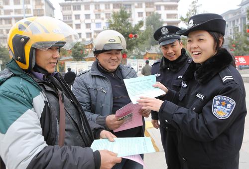 1月10日,在广西融水苗族自治县芦笙文化广场,融水县公安局民警庞荣(右一)向居民介绍如何正确拨打110电话。新华社发(龙涛 摄)
