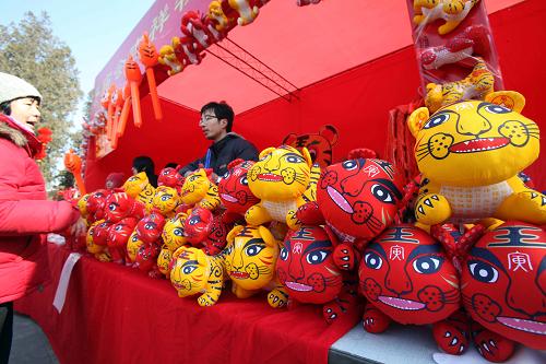2月13日,游人在北京地坛公园庙会选购吉祥虎。新华社发(陈晓根 摄)