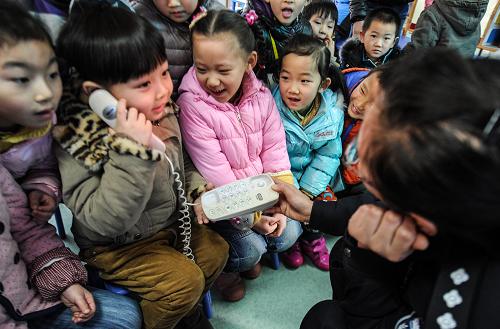 1月10日,合肥市竹荫里派出所民警刘景怡(右)在教孩子们如何拨打报警电话。新华社记者 杜宇 摄